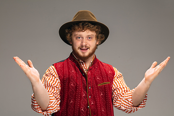 Image showing Happy smiling man dressed in traditional Austrian or Bavarian costume gesturing isolated on grey studio background