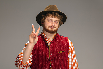 Image showing Happy smiling man dressed in traditional Austrian or Bavarian costume gesturing isolated on grey studio background
