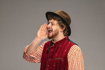 Image showing Happy smiling man dressed in traditional Austrian or Bavarian costume gesturing isolated on grey studio background