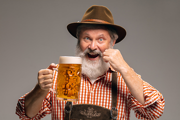 Image showing Happy senior man dressed in traditional Austrian or Bavarian costume gesturing isolated on grey studio background