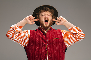 Image showing Happy smiling man dressed in traditional Austrian or Bavarian costume gesturing isolated on grey studio background