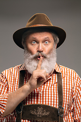 Image showing Happy senior man dressed in traditional Austrian or Bavarian costume gesturing isolated on grey studio background