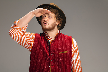 Image showing Happy smiling man dressed in traditional Austrian or Bavarian costume gesturing isolated on grey studio background