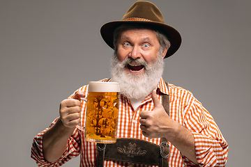 Image showing Happy senior man dressed in traditional Austrian or Bavarian costume gesturing isolated on grey studio background