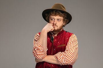 Image showing Happy smiling man dressed in traditional Austrian or Bavarian costume gesturing isolated on grey studio background