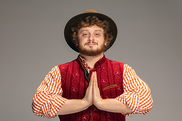 Image showing Happy smiling man dressed in traditional Austrian or Bavarian costume gesturing isolated on grey studio background