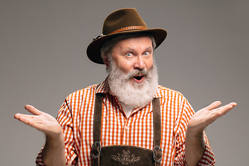 Image showing Happy senior man dressed in traditional Austrian or Bavarian costume gesturing isolated on grey studio background