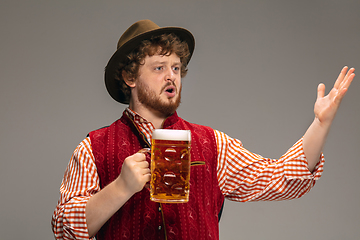 Image showing Happy smiling man dressed in traditional Austrian or Bavarian costume gesturing isolated on grey studio background