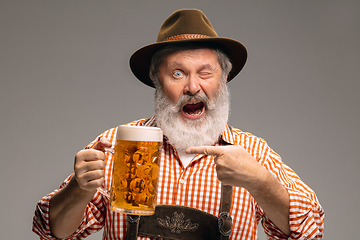 Image showing Happy senior man dressed in traditional Austrian or Bavarian costume gesturing isolated on grey studio background