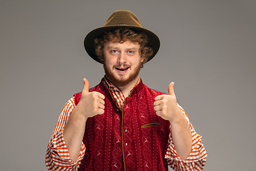 Image showing Happy smiling man dressed in traditional Austrian or Bavarian costume gesturing isolated on grey studio background