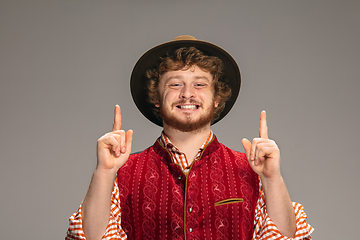 Image showing Happy smiling man dressed in traditional Austrian or Bavarian costume gesturing isolated on grey studio background