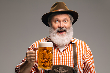 Image showing Happy senior man dressed in traditional Austrian or Bavarian costume gesturing isolated on grey studio background