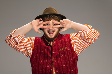 Image showing Happy smiling man dressed in traditional Austrian or Bavarian costume gesturing isolated on grey studio background