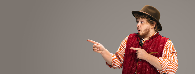 Image showing Happy smiling man dressed in traditional Austrian or Bavarian costume gesturing isolated on grey studio background