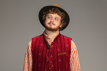 Image showing Happy smiling man dressed in traditional Austrian or Bavarian costume gesturing isolated on grey studio background