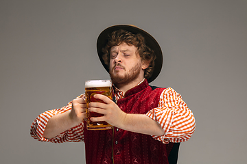 Image showing Happy smiling man dressed in traditional Austrian or Bavarian costume gesturing isolated on grey studio background