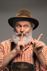 Image showing Happy senior man dressed in traditional Austrian or Bavarian costume gesturing isolated on grey studio background