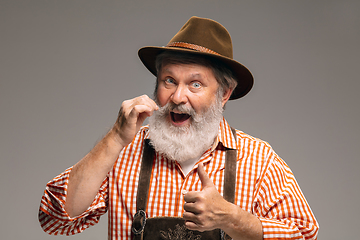 Image showing Happy senior man dressed in traditional Austrian or Bavarian costume gesturing isolated on grey studio background