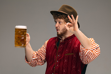 Image showing Happy smiling man dressed in traditional Austrian or Bavarian costume gesturing isolated on grey studio background