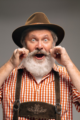 Image showing Happy senior man dressed in traditional Austrian or Bavarian costume gesturing isolated on grey studio background