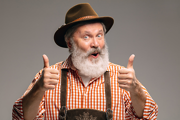 Image showing Happy senior man dressed in traditional Austrian or Bavarian costume gesturing isolated on grey studio background