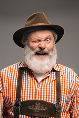 Image showing Happy senior man dressed in traditional Austrian or Bavarian costume gesturing isolated on grey studio background