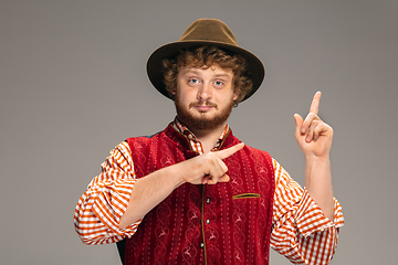 Image showing Happy smiling man dressed in traditional Austrian or Bavarian costume gesturing isolated on grey studio background