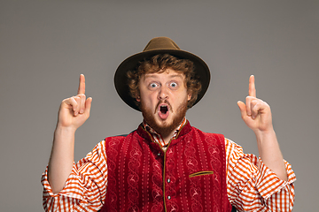 Image showing Happy smiling man dressed in traditional Austrian or Bavarian costume gesturing isolated on grey studio background