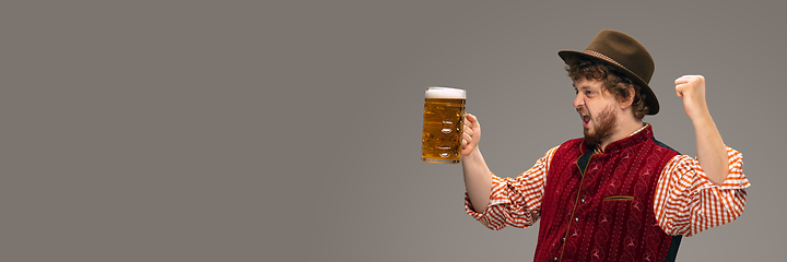 Image showing Happy smiling man dressed in traditional Austrian or Bavarian costume gesturing isolated on grey studio background