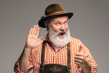 Image showing Happy senior man dressed in traditional Austrian or Bavarian costume gesturing isolated on grey studio background