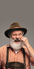 Image showing Happy senior man dressed in traditional Austrian or Bavarian costume gesturing isolated on grey studio background