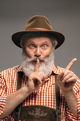Image showing Happy senior man dressed in traditional Austrian or Bavarian costume gesturing isolated on grey studio background