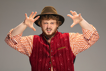 Image showing Happy smiling man dressed in traditional Austrian or Bavarian costume gesturing isolated on grey studio background