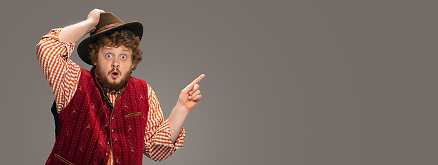 Image showing Happy smiling man dressed in traditional Austrian or Bavarian costume gesturing isolated on grey studio background