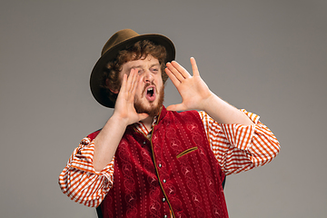 Image showing Happy smiling man dressed in traditional Austrian or Bavarian costume gesturing isolated on grey studio background