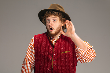 Image showing Happy smiling man dressed in traditional Austrian or Bavarian costume gesturing isolated on grey studio background