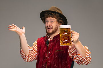 Image showing Happy smiling man dressed in traditional Austrian or Bavarian costume gesturing isolated on grey studio background