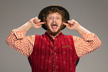 Image showing Happy smiling man dressed in traditional Austrian or Bavarian costume gesturing isolated on grey studio background