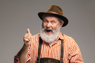 Image showing Happy senior man dressed in traditional Austrian or Bavarian costume gesturing isolated on grey studio background