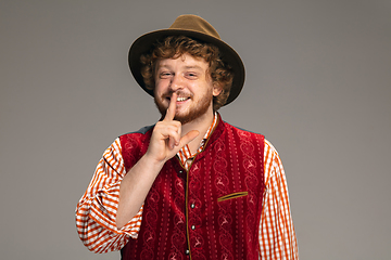 Image showing Happy smiling man dressed in traditional Austrian or Bavarian costume gesturing isolated on grey studio background