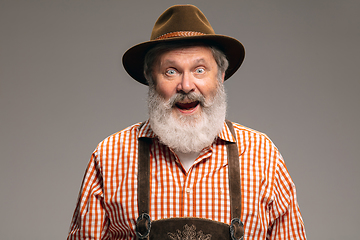 Image showing Happy senior man dressed in traditional Austrian or Bavarian costume gesturing isolated on grey studio background