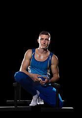 Image showing Muscular male gymnast training in gym, flexible and active. Caucasian fit guy, athlete in blue sportswear isolated on black