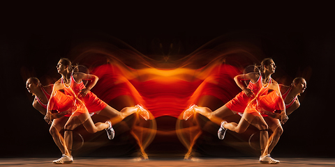 Image showing Young woman playing tennis isolated on black with fire flames. Youth, flexibility, power and energy. Reflection, mirror, strobe light