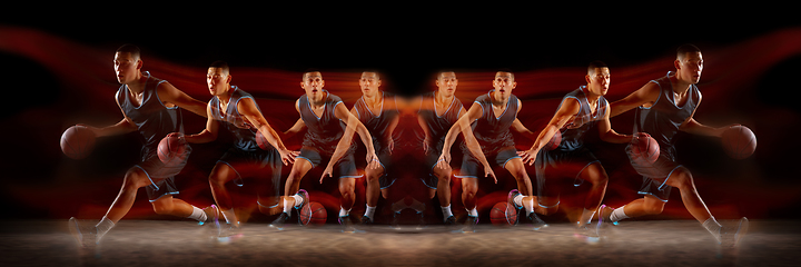 Image showing Young purposeful basketball player training in action isolated on black background with fire flames. Mirror, strobe light effect, reflection