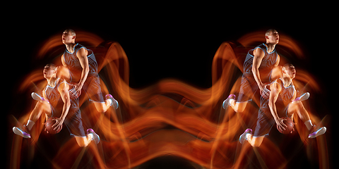 Image showing Young purposeful basketball player training in action isolated on black background with fire flames. Mirror, strobe light effect, reflection