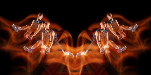 Image showing Young purposeful basketball player training in action isolated on black background with fire flames. Mirror, strobe light effect, reflection