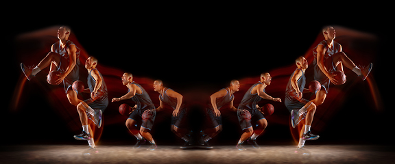 Image showing Young purposeful basketball player training in action isolated on black background with fire flames. Mirror, strobe light effect, reflection