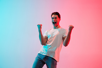 Image showing Young caucasian man\'s portrait on gradient blue-pink studio background in neon light