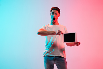 Image showing Young caucasian man\'s portrait on gradient blue-pink studio background in neon light