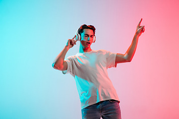 Image showing Young caucasian man\'s portrait on gradient blue-pink studio background in neon light